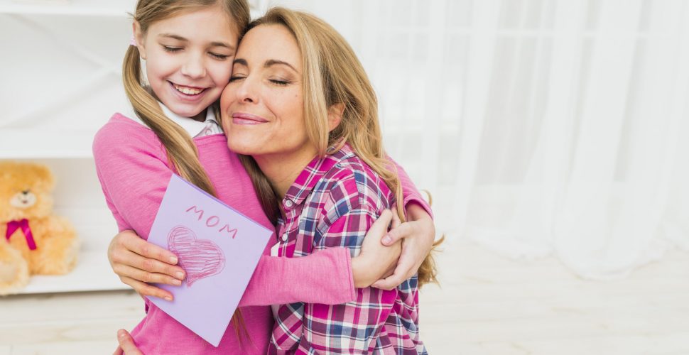 happy-mother-with-greeting-card-hugging-daughter