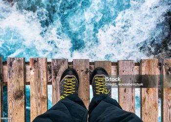 feet in hiking boots on the edge of an old wooden bridge